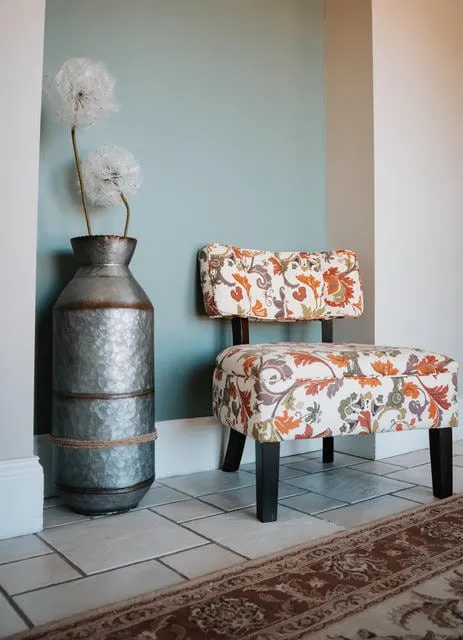 A corner of the waiting area with a tall vase and an upholstered bench.