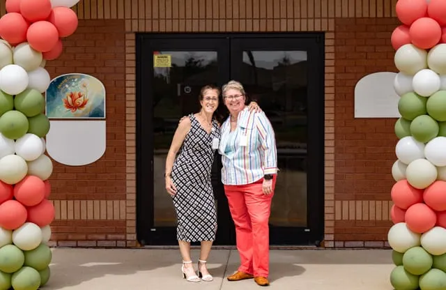 Rachel Morgan and Jennifer Schenck outside the practice entrance, framed by an arch of balloons on opening day.