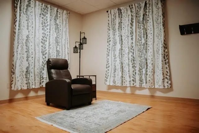 A quiet room with a leather recliner and a floor lamp.
